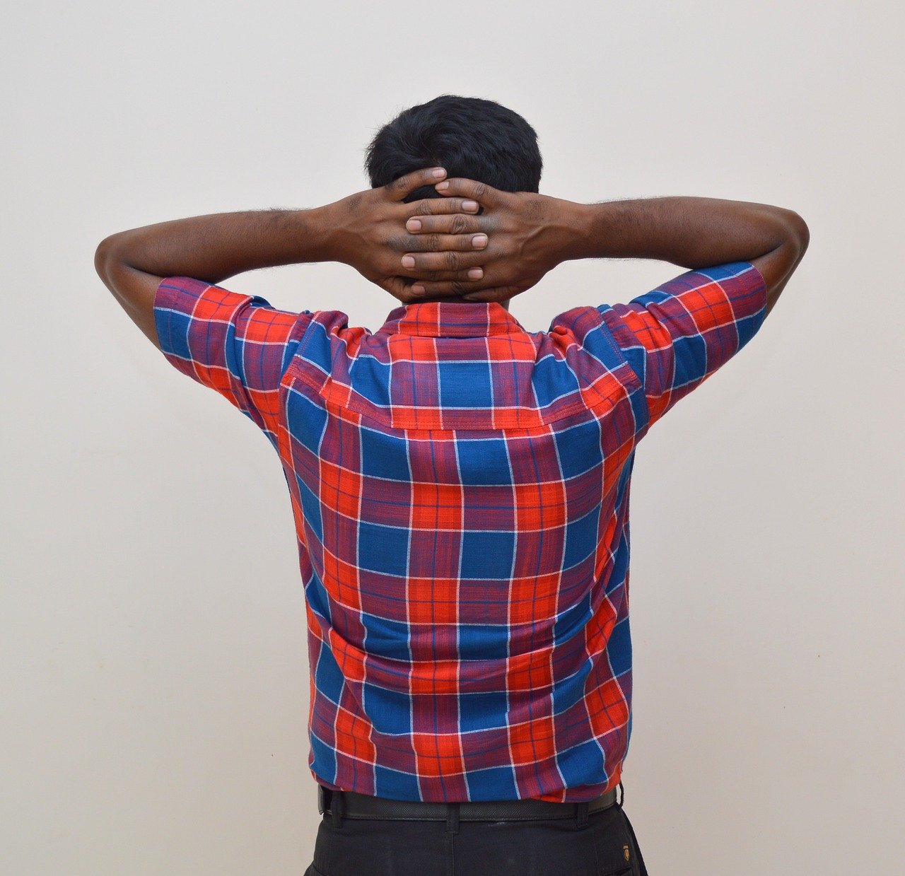 Image of a stressed out man with his crossed arms behind his head.