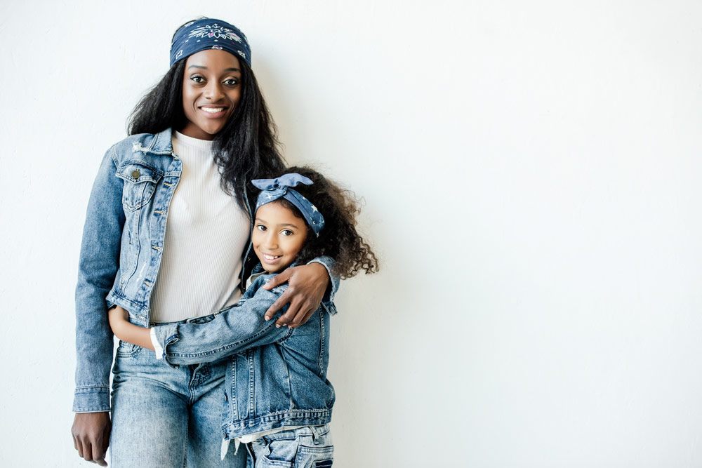 Photo of a Black woman and a Black girl posing together, wearing stylish denim outfits.