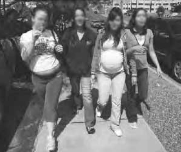 An image of four young pregnant woman walking on a sidewalk; their faces are blurred.