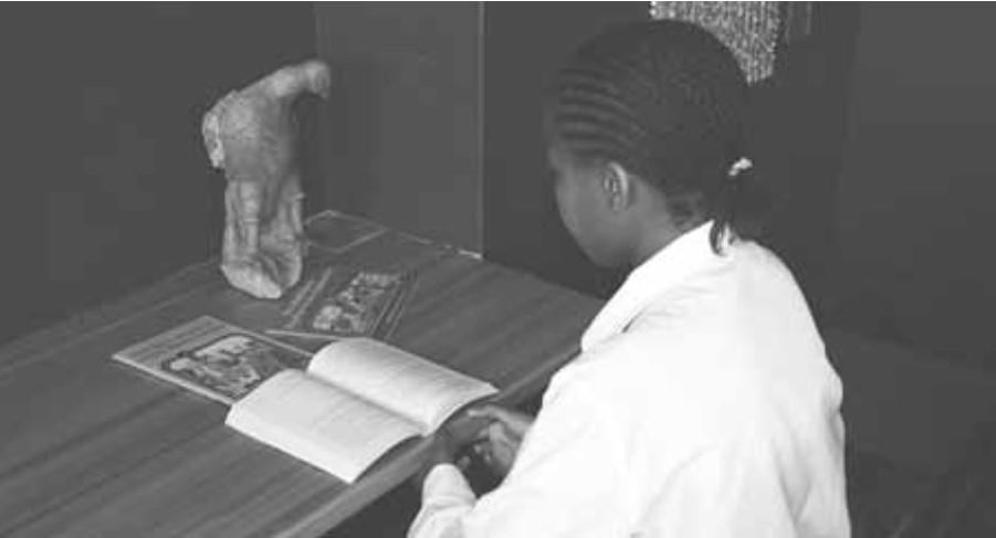 A child studies a book at a desk.