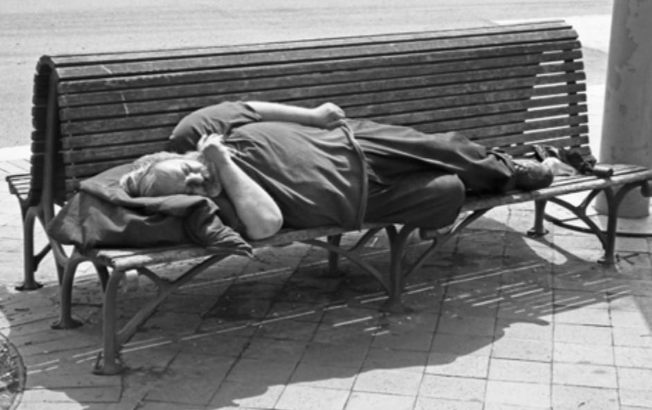 Photo of a man sleeping on a public bench.