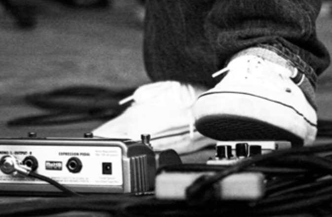 Photo of a local musician using his feet to control sound equipment during a performance.