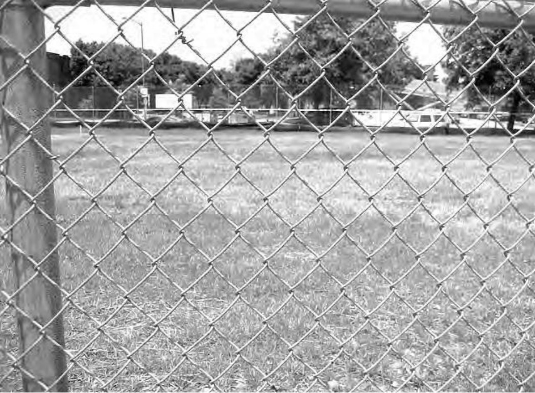 Photo of a vacant lot through a chain fence.