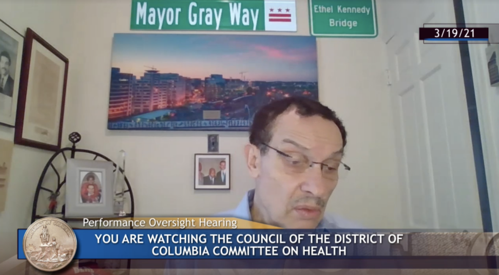 Image shows Councilmember Vincent Gray of Ward 7 at the virtual performance oversight hearing for D.C. Health on March 19. Background is a home office with various posters.