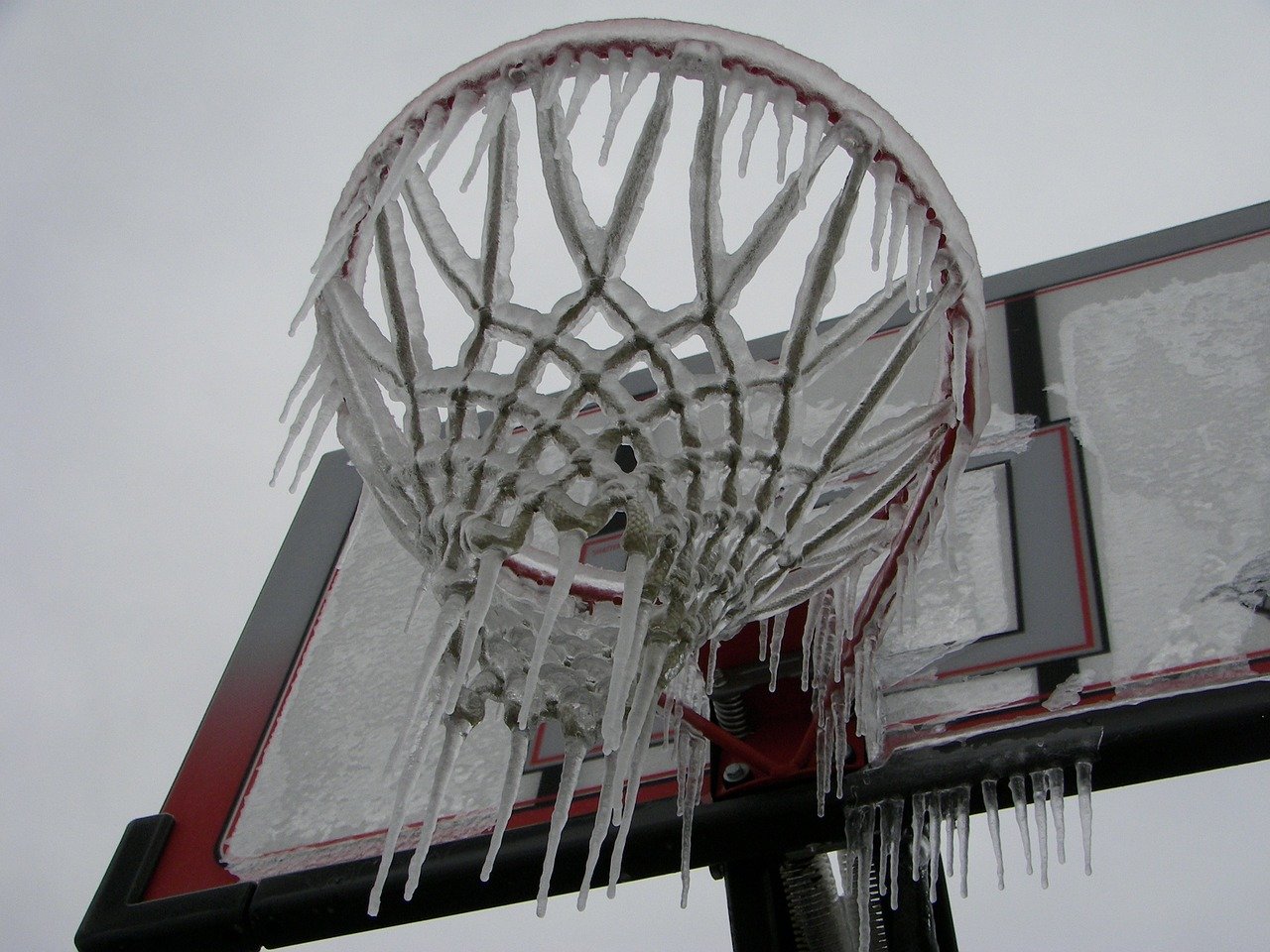 An image of a basketball rim and net covered in ice and snow.