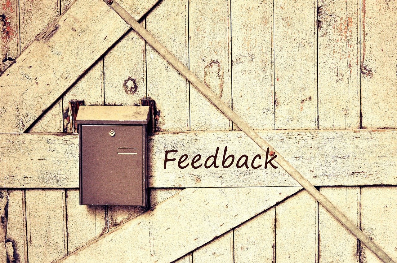 Image of a letter box with the word "feedback" painted on the fence it is hung on.