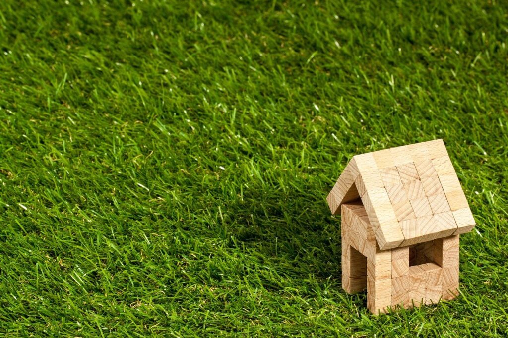 Photo of a small house made out of building blocks sitting in a grass lawn.