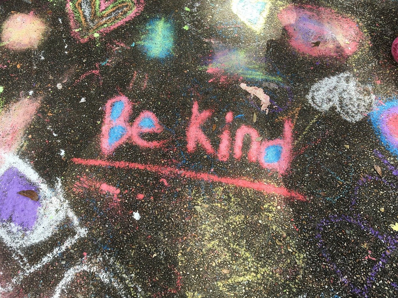 An image of a sidewalk chalk drawing with the phrase "Be Kind" in the center