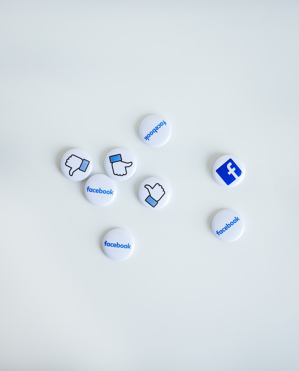 Photo shows buttoms with the facebook logo and thumbs up sign againist a white background