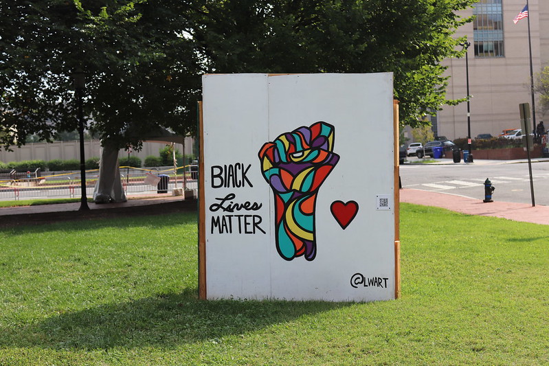 Photo of a Black Lives Matter mural in Washington, DC. It shows a raised first in multiple colors with a heart next to it.