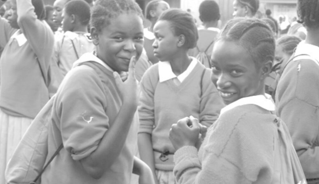 Photo of two young Kenyan school girls smiling at the camera.