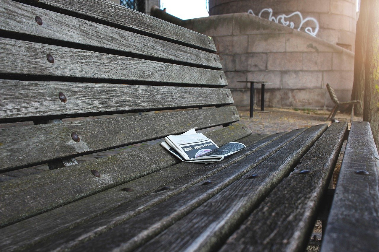 Photo of a newspaper sitting on a park bench.