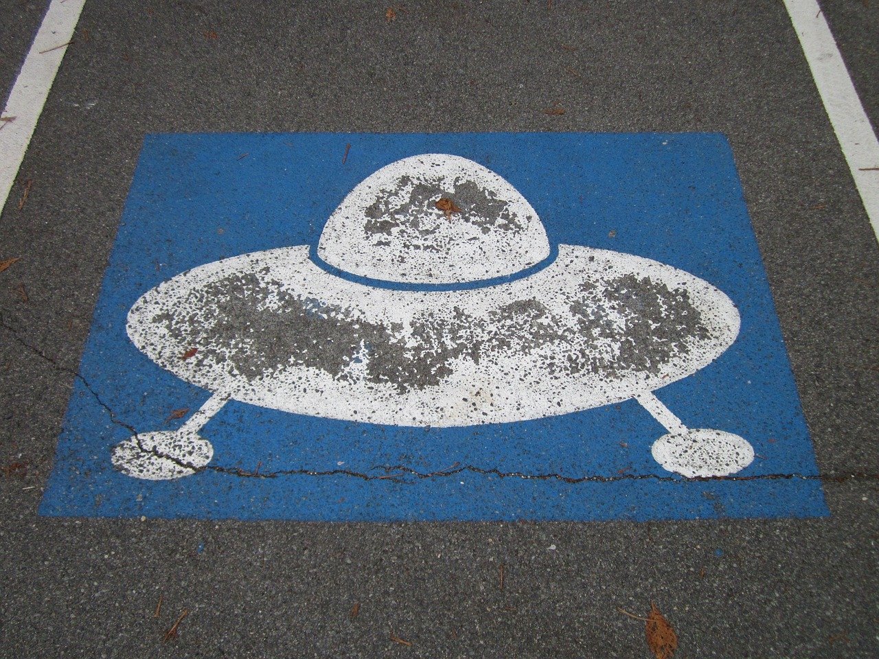 Photo of a parking space with a UFO landing sign on it.