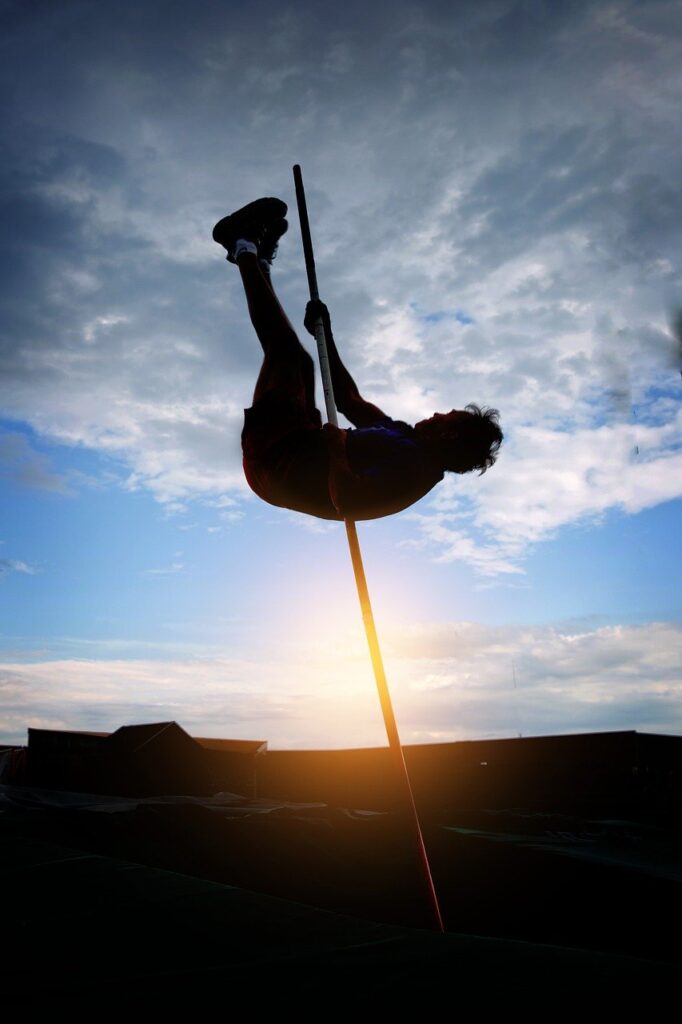 Photo of a pole vaulter reaching high up into the air.