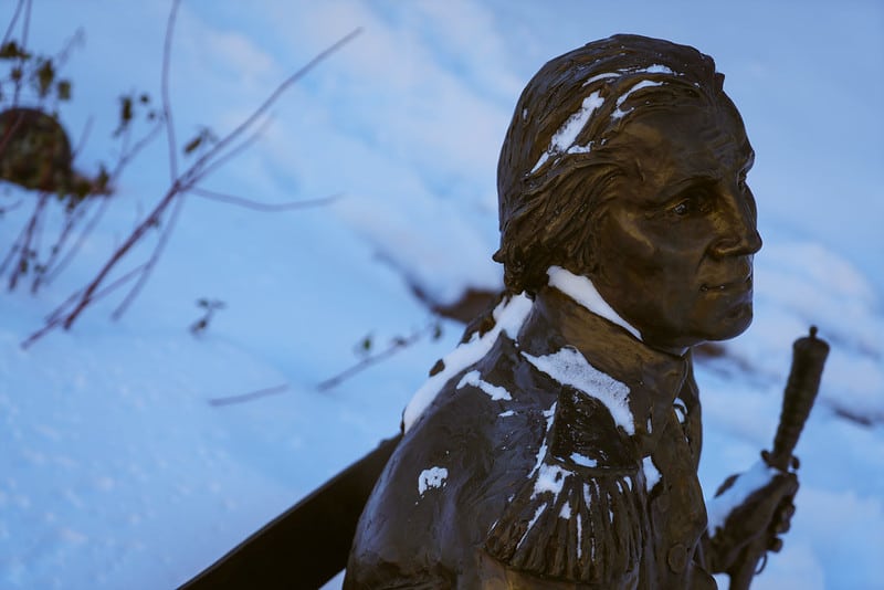 A statue of George Washington lightly blanketed in snow