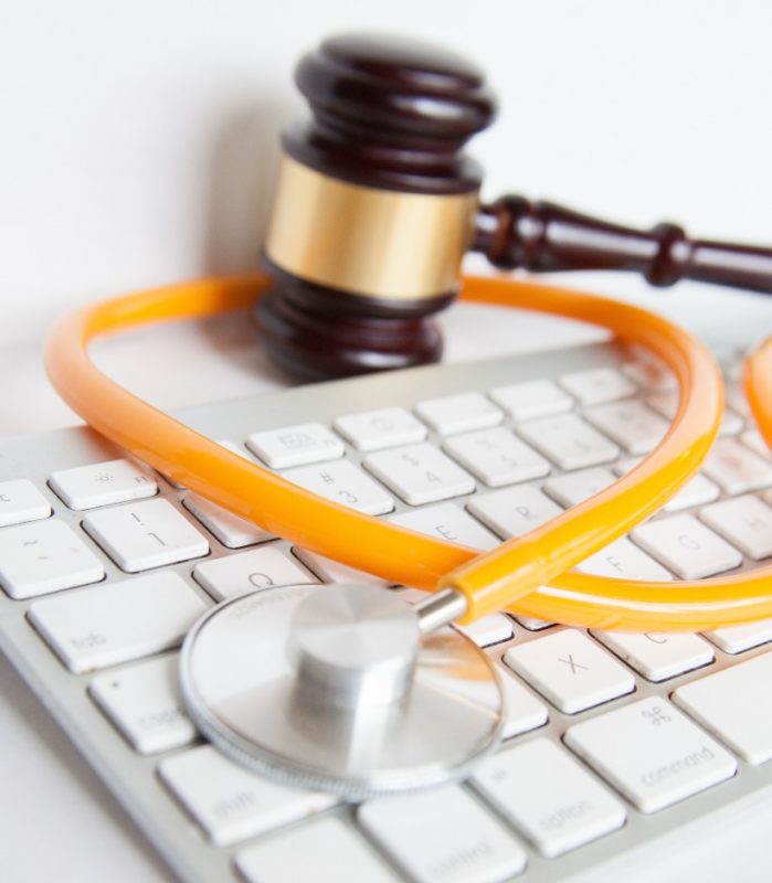 Photo of a gavel sitting next to a keyboard and a stethoscope