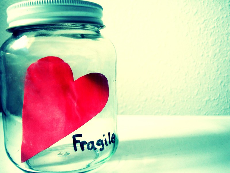 A glass jar with a paper heart inside; "fragile" is written on the outside