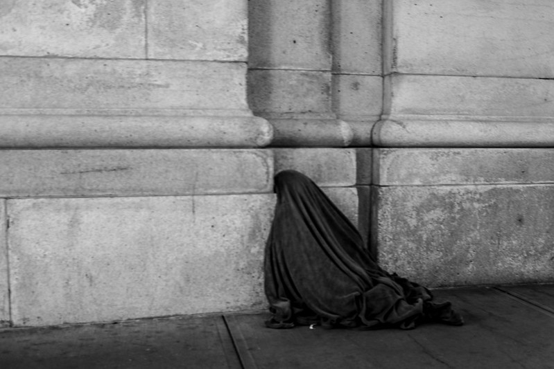 A person huddling under a blanket in Washington, DC