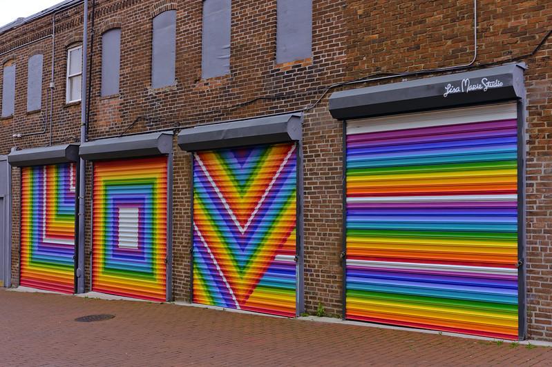 A mural on garage doors written in rainbow colors that says "LOVE" in rainbows, with each garage door being a different letter.