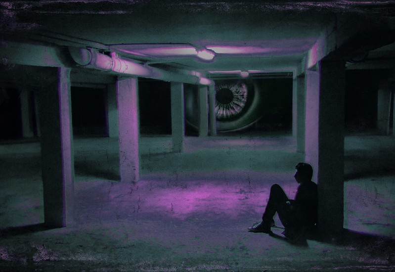 An illustration depicting a man slumped against a wall at night; an eye is gazing at him, giving a strong sense of anxiety.
