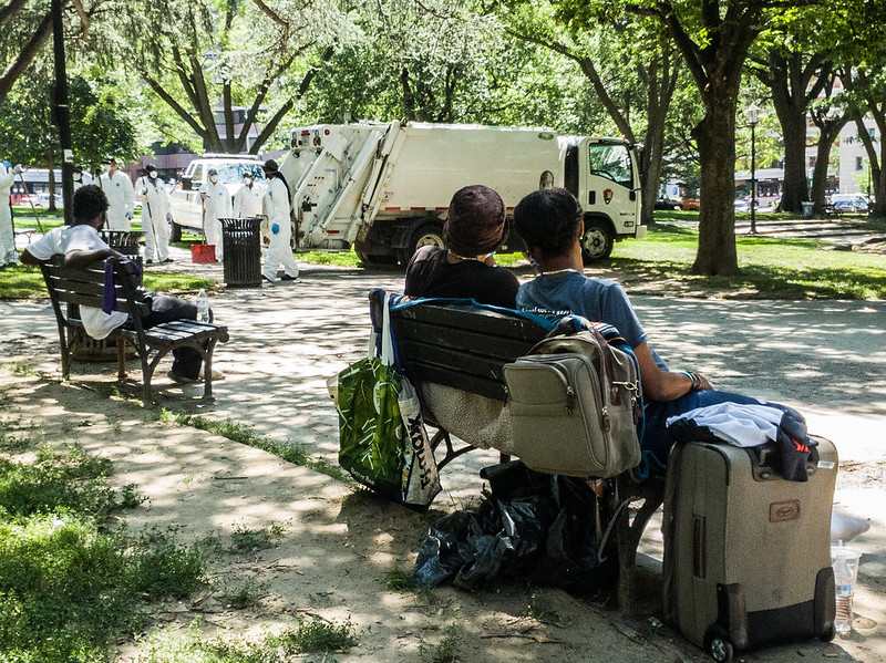 Displaced residents sit on park benches with their belongings and watch as officials "clean-up" Franklin Square.