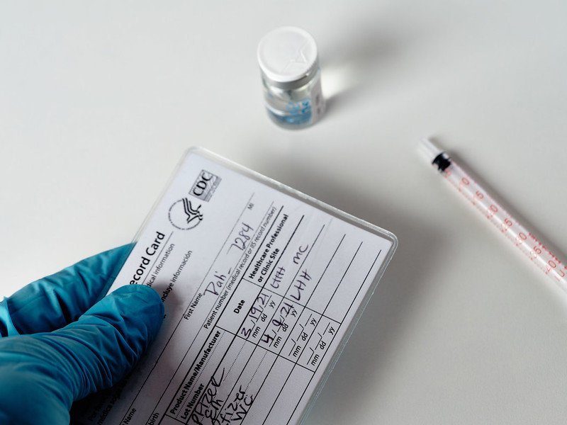Photo of a CDC COVID-19 vaccination card and a vial of vaccine