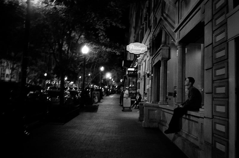 Black and white photo of 7th St NW in Washington, DC. A man gazes into the distance.
