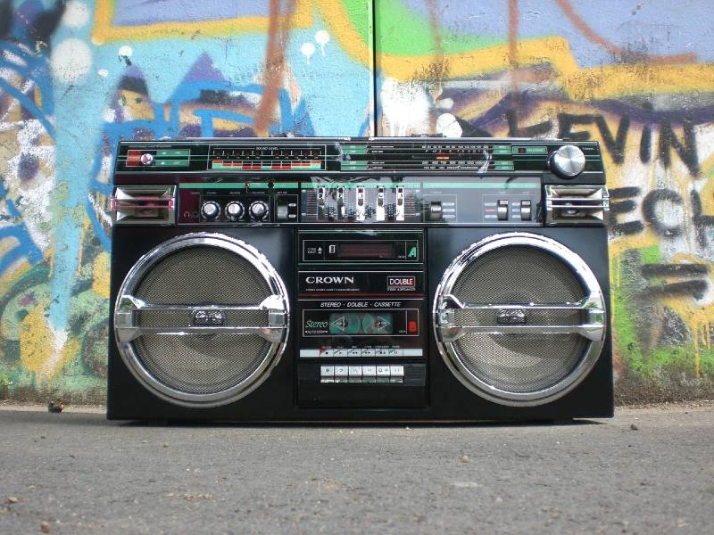 Photo of a boombox in front of a wall of graffiti.
