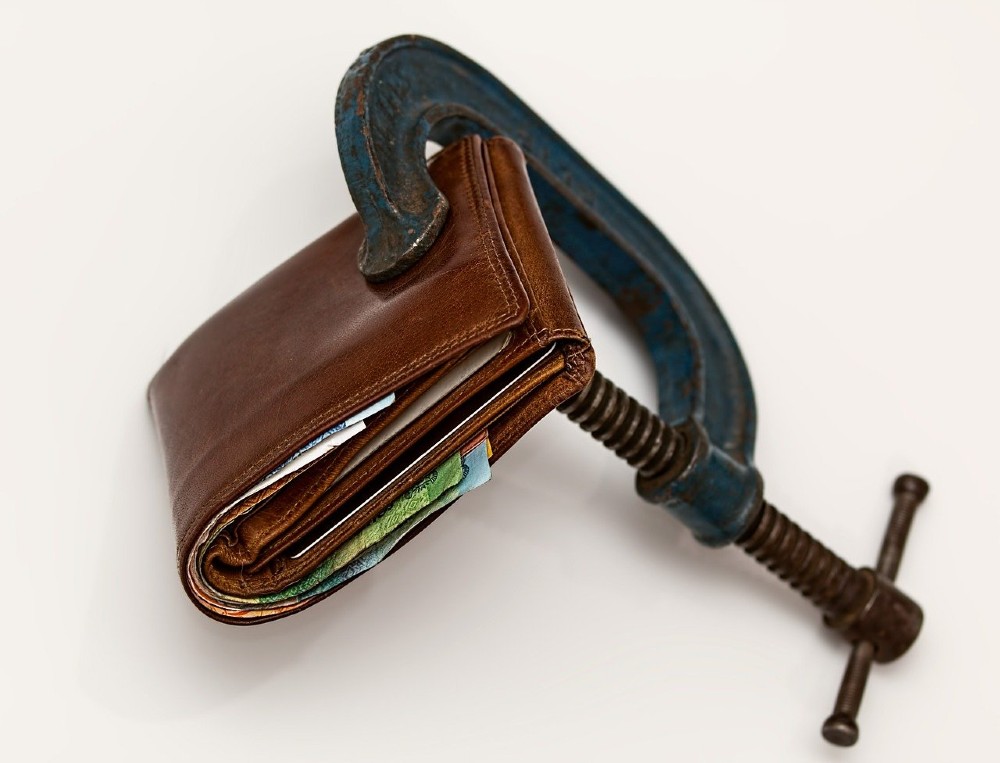 Photo of a vice squeezing a wallet shut.