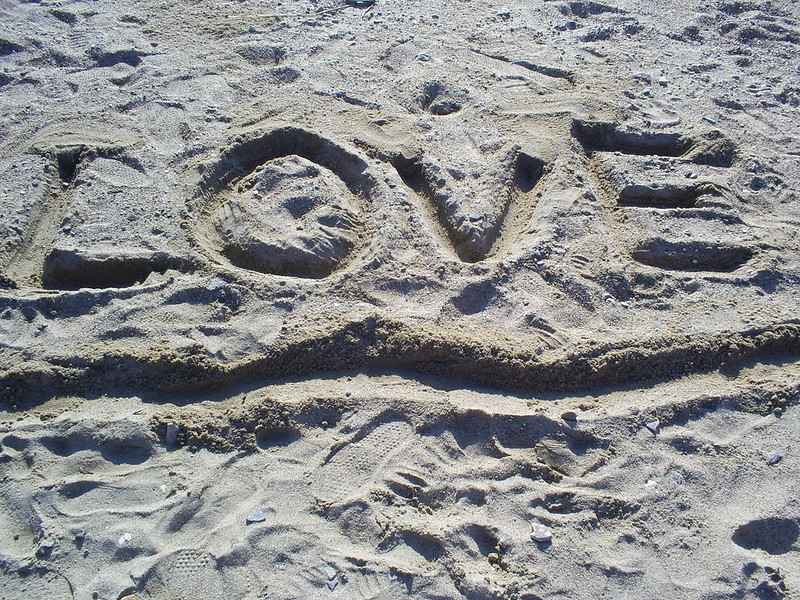 Photo of the word "LOVE" dug into sand on a beach