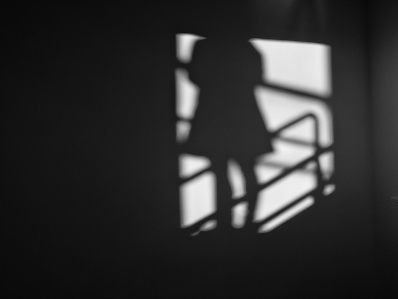 Photo of the shadow of a woman standing in a stairwell.