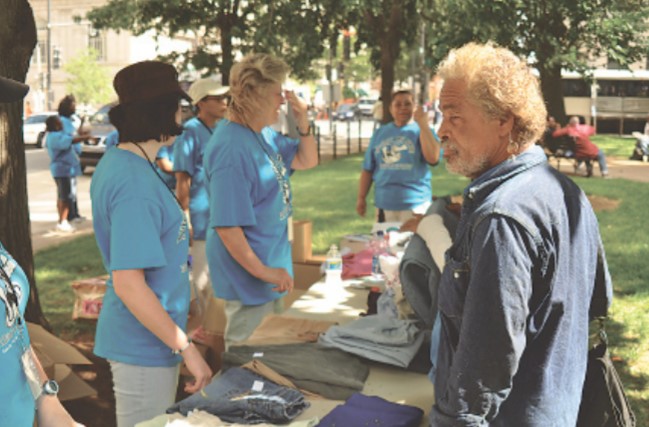 A guest chooses from the free clothing offered at a clothing table.