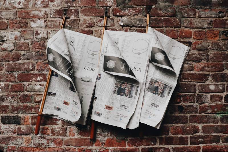 Photo of newspapers hanging on an exposed brick wall