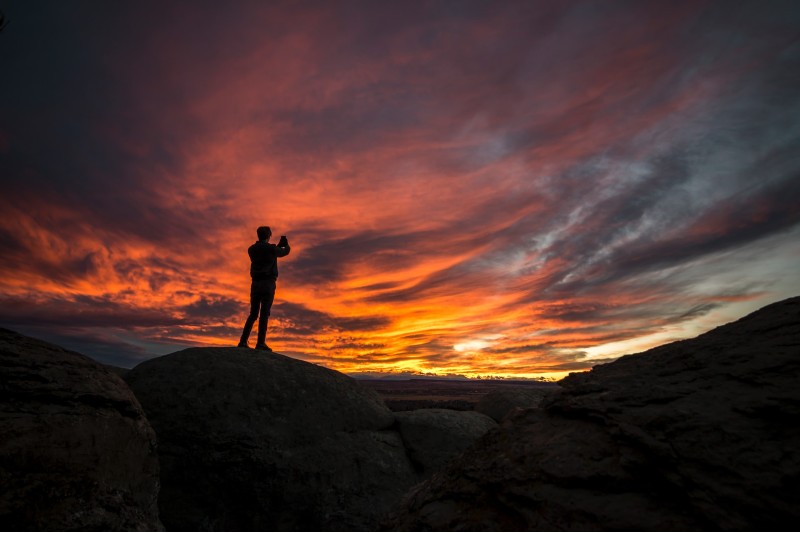 Photo of a shadowed man taking a photo of a sunset