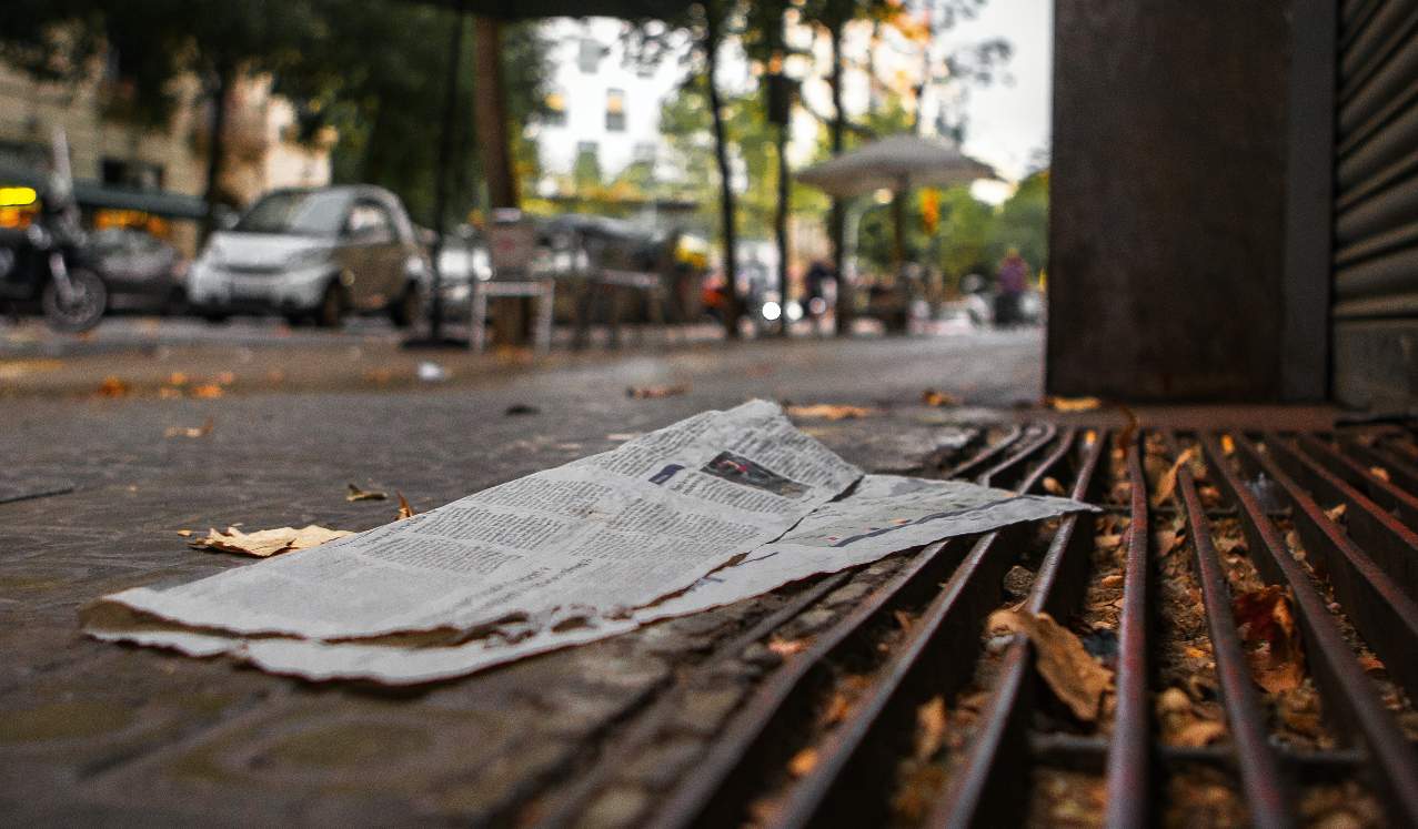 Photo of a newspaper lying on the sidewalk.