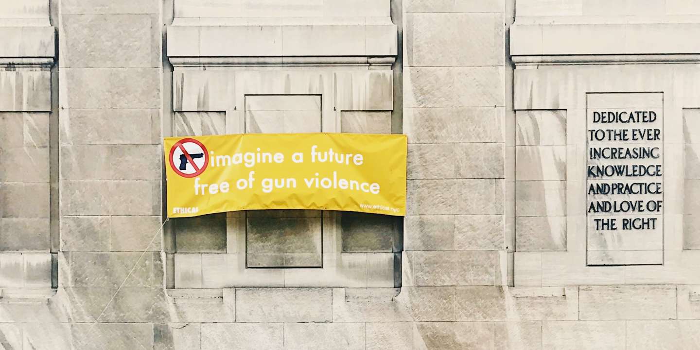 Photo of a yellow banner that says "Imagine a future free of gun violence" hanging on a building.
