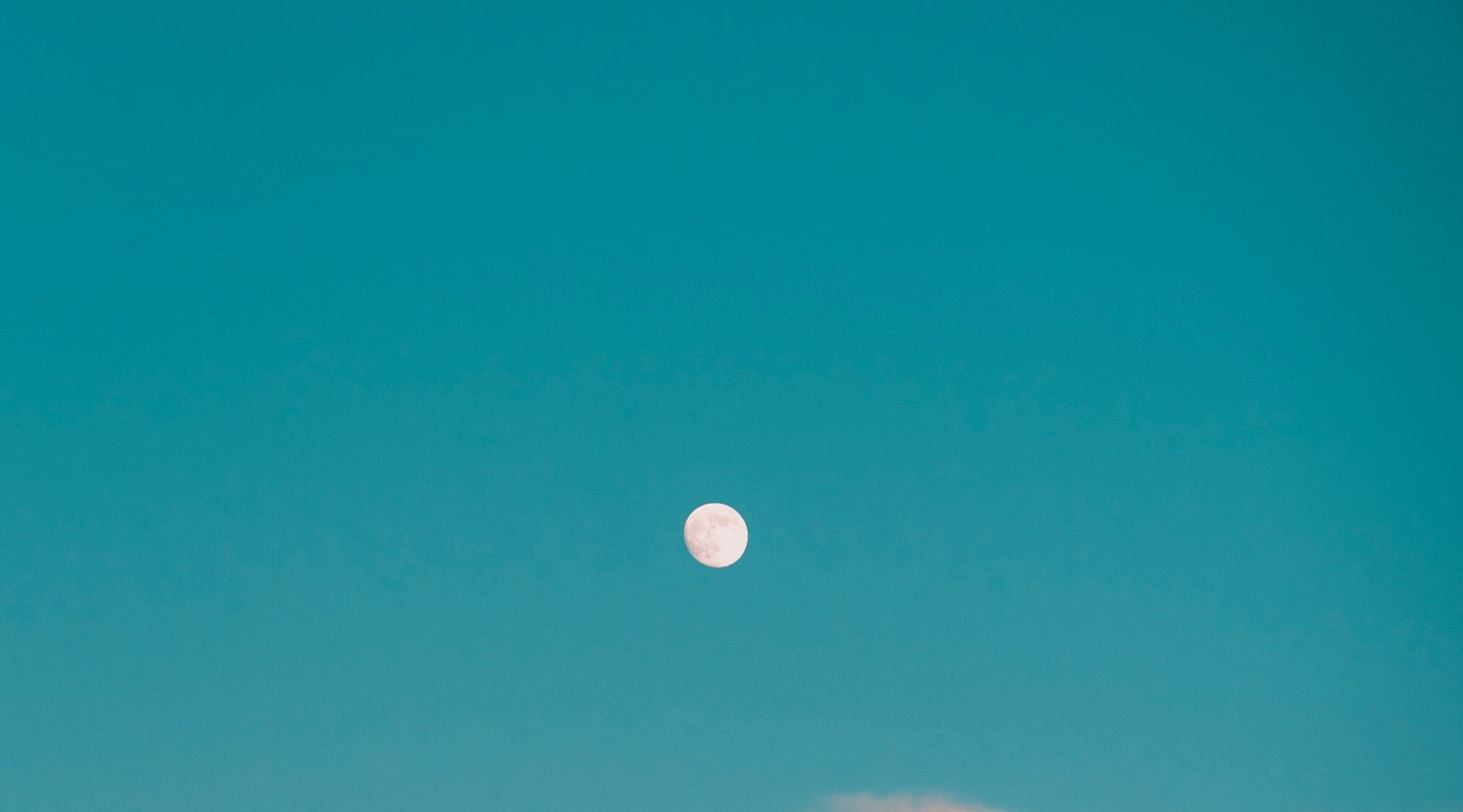 Photo of the moon against a blue sky.