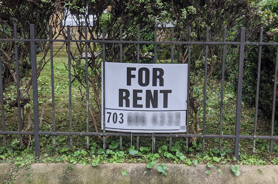 "For Rent" sign in the front yard of a rowhouse