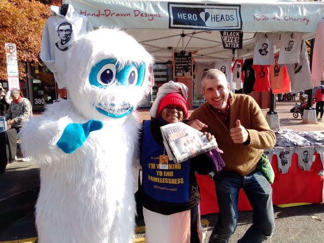 A photo of Juliene Kengnie standing with a person dressed in a white and blue monster costume and a man on her right.