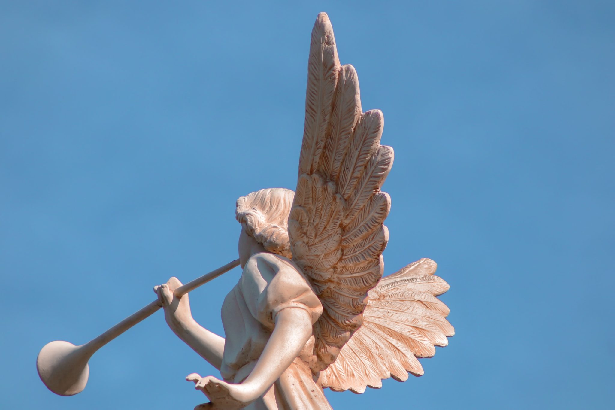 Photo of a statue of an angel playing a horn.
