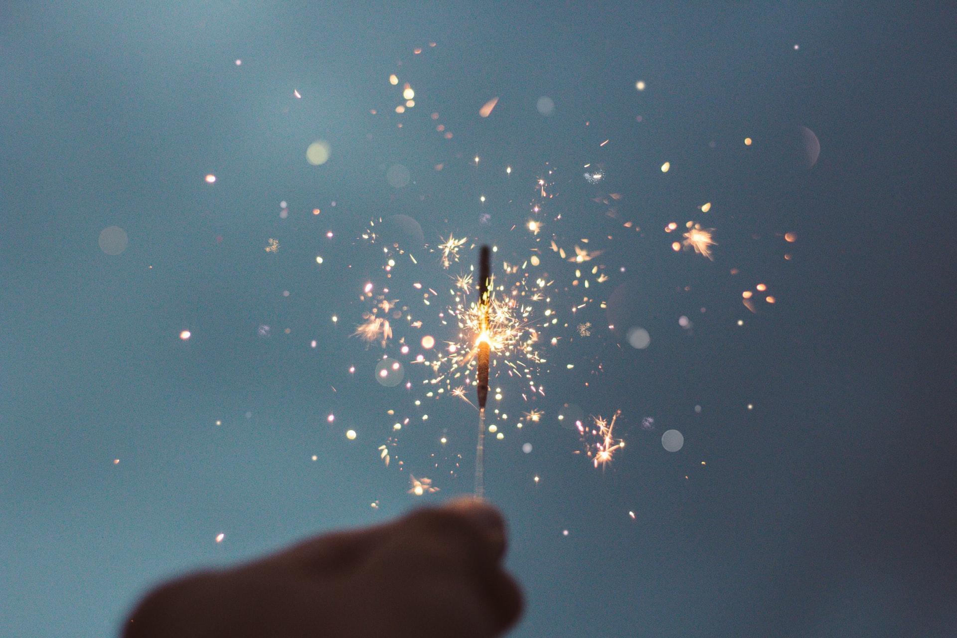 Photo of a hand holding a sparkler that is on fire.