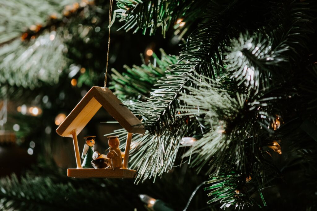 Photo of a nativity Christmas ornament hanging from a Christmas tree.