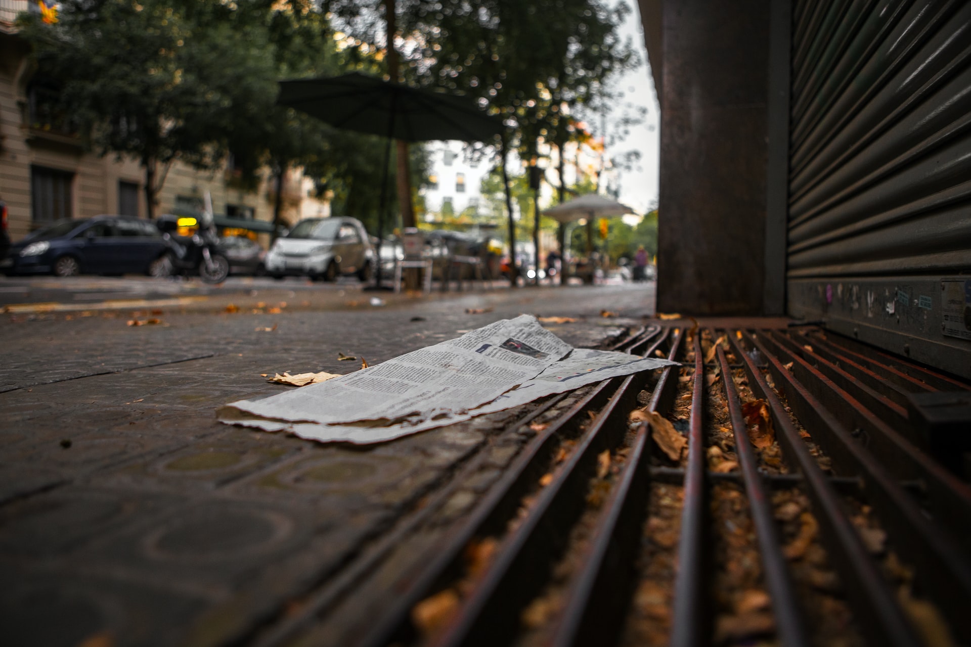 A photo of a street with a discarded newspaper in the foreground.