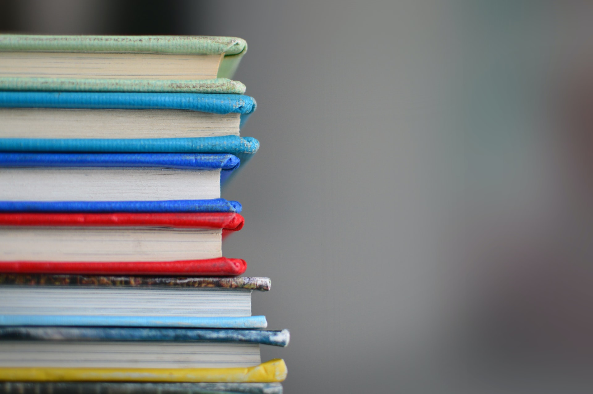 Photo of a stack of books to the left of the frame in varying colors.