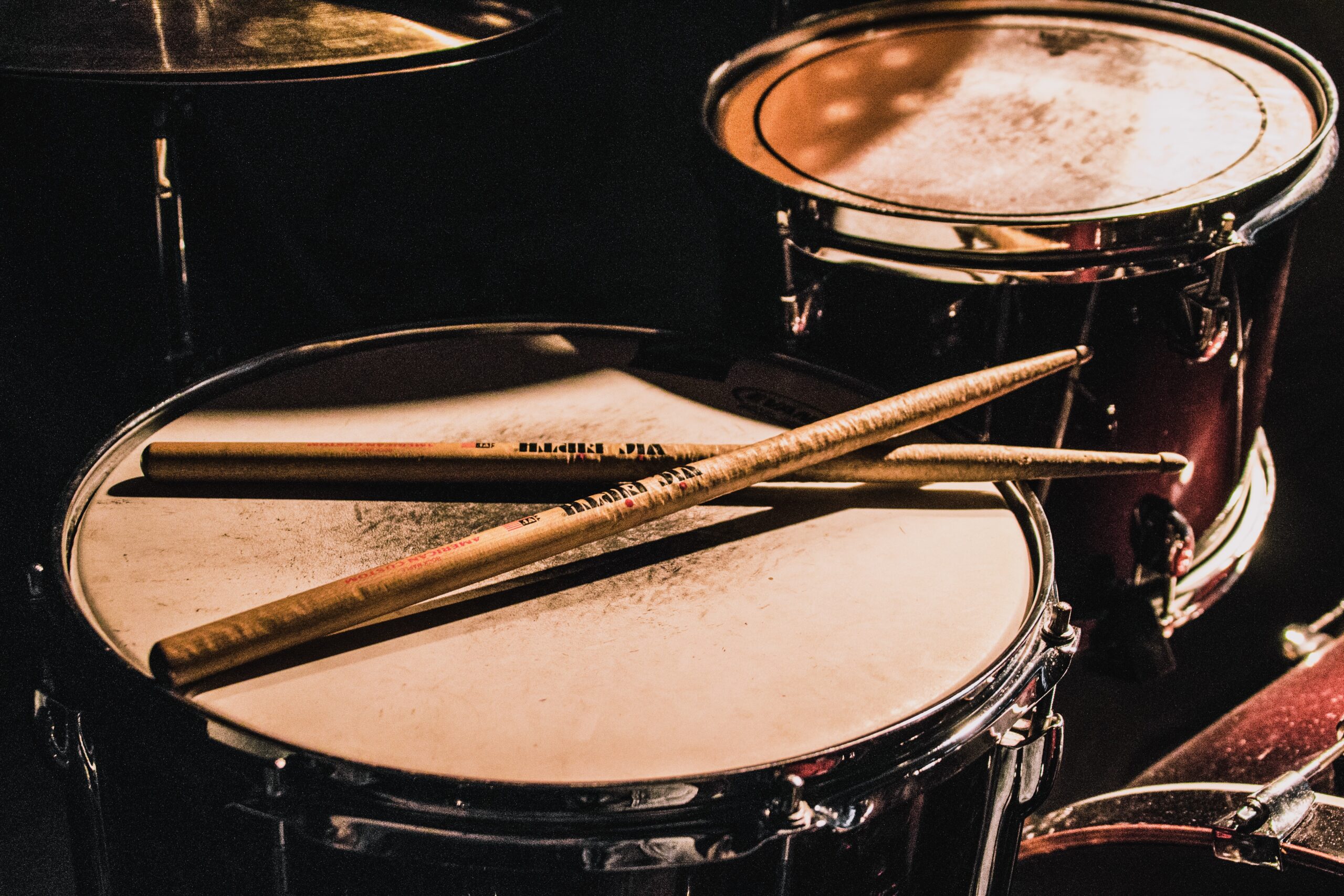 Photo of two drumsticks resting on top of a drum set.