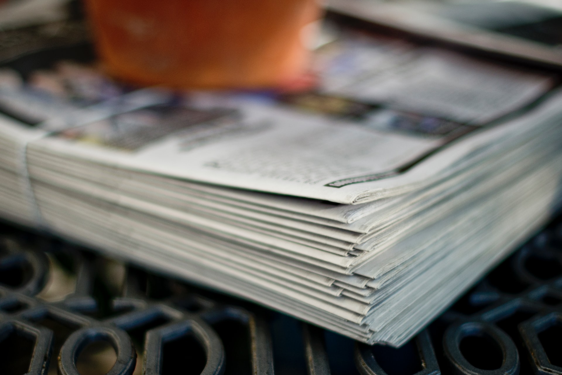 A phot of a stack of newspapers with an apple on top.