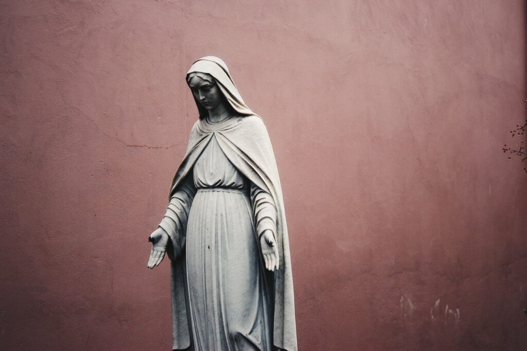 A photo of a statue of a woman wearing a dress and cloak.