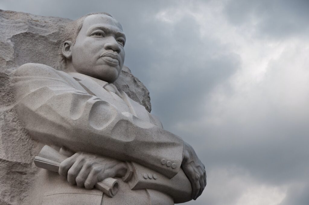A photo of a statue of Dr. Martin Luther King Jr. under white clouds during the daytime.