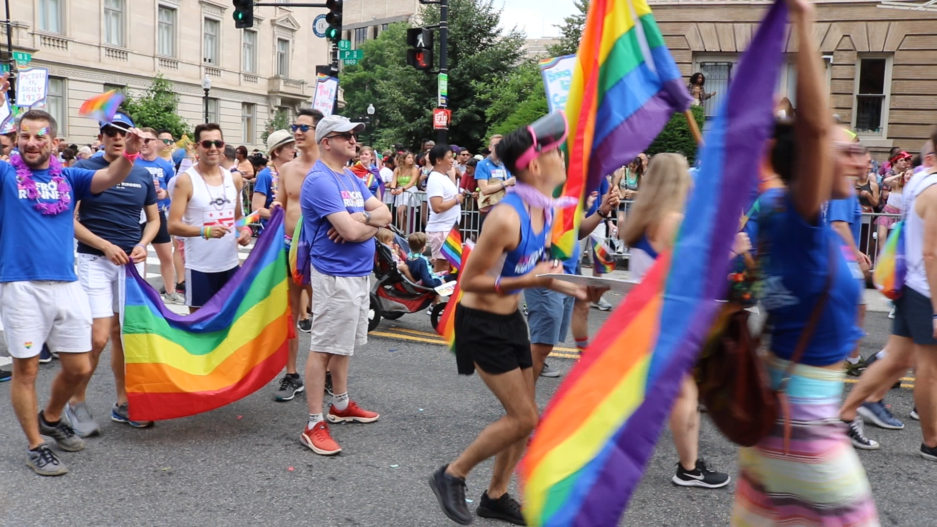 A group of people in a parade with rainbow flags.