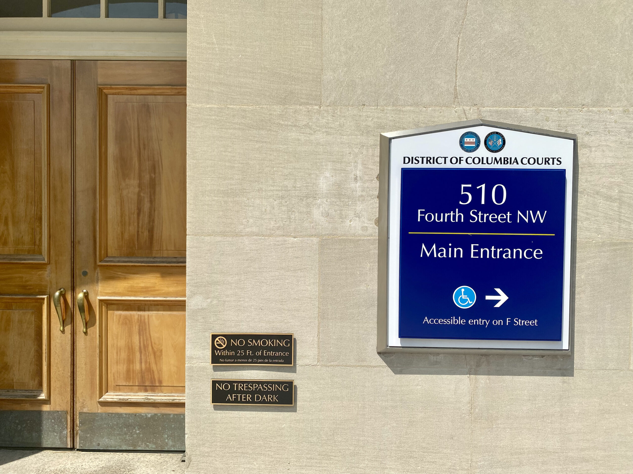A blue sign reading "District of Columbia Courts, 510" next to a closed wooden door.